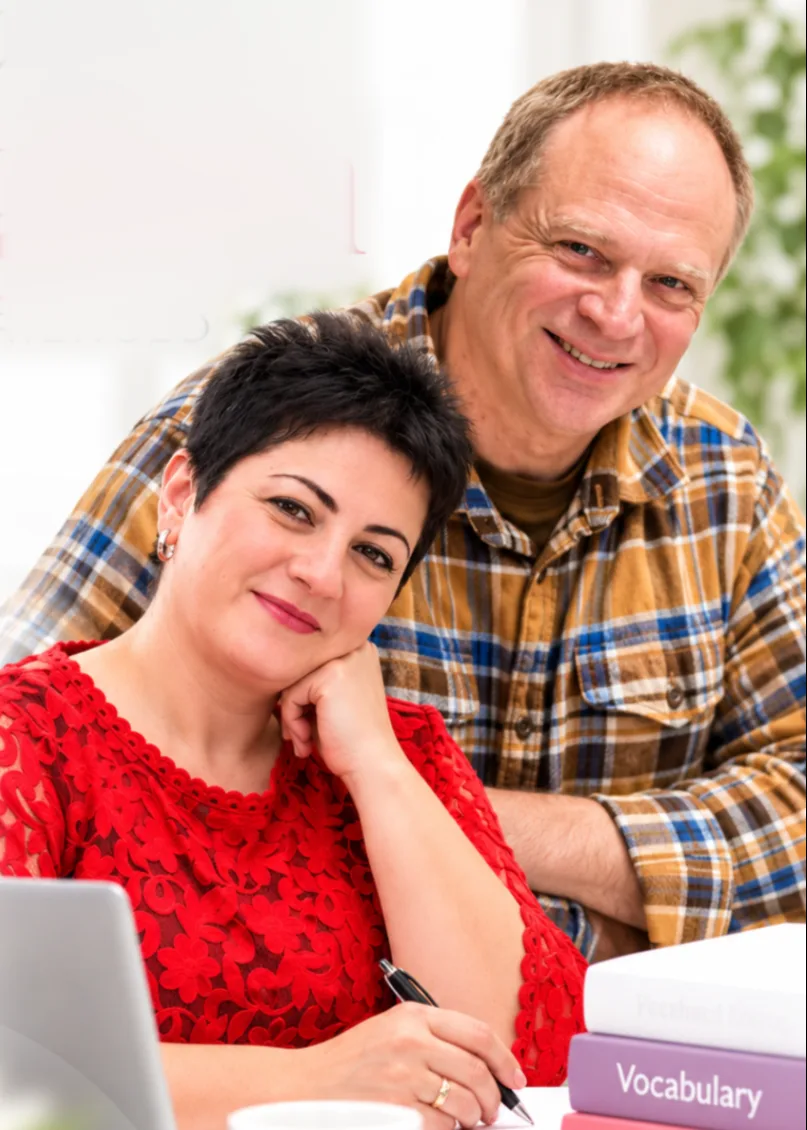 Terralingua's two teachers smiling together at a desk with books and a laptop